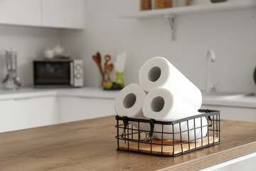 Basket with rolls of paper towels on table in kitchen, closeup