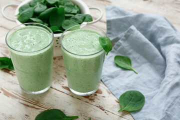 Glasses of fresh spinach smoothie on white wooden background