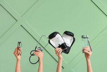 Female hands with eyeglasses, stethoscope, boxing gloves and water bottle on green background....