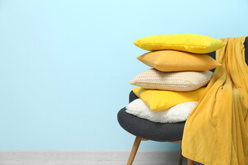 Stack of cushions and plaid on armchair near blue wall in room