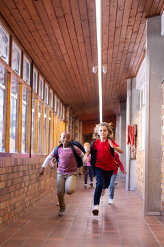 Running in school hallway, diverse children with backpacks enjoying recess time, copy space