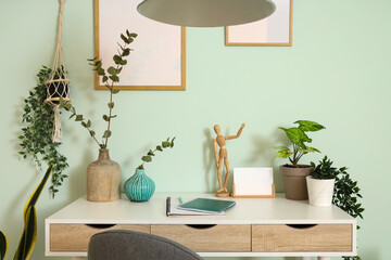 Wooden mannequin with green plants on desk in office