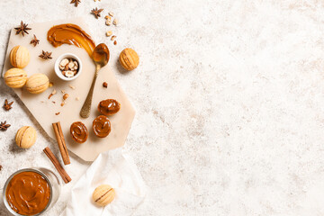 Board with tasty walnut shaped cookies, boiled condensed milk and ingredients on white grunge table