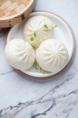 Freshly cooked chinese baozi on a white stone background, vertical shot with space, elevated view, selective focus