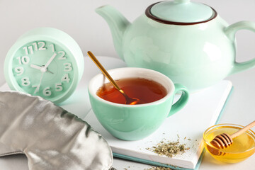 Sleep mask, alarm clock and tea set on grey background, closeup