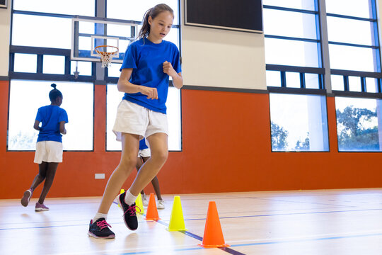 Fototapeta Running through cones, girl participating in school gym class activity
