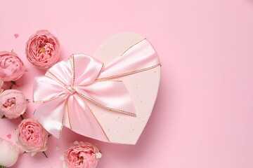 Beautiful pink peony roses with gift box on a colored background