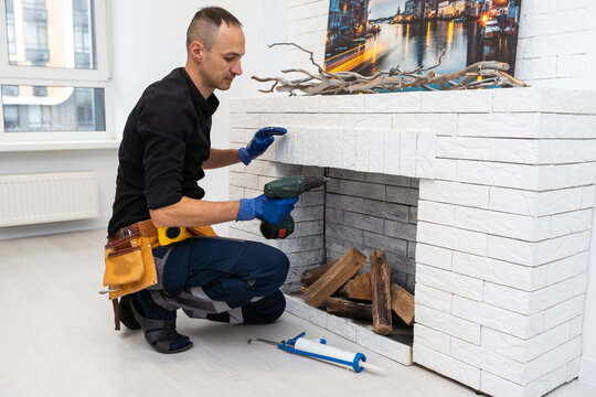 Worker building brick stove or fireplace checking it with spirit level