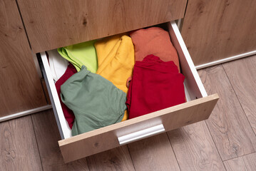 folded clothes are in the drawer of the wardrobe