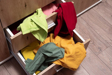 pile of clothes lies in the open drawers of the closet. Scattered things around