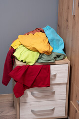 pile of clothes lies in the open drawers of the closet. Scattered things around