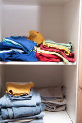 neatly folded clothes lying on the shelves of the wardrobe