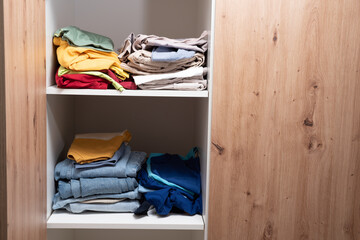 neatly folded clothes lying on the shelves of the wardrobe