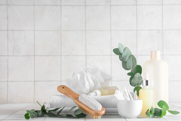 Composition with cosmetic products, bath supplies and eucalyptus branches on light tile background