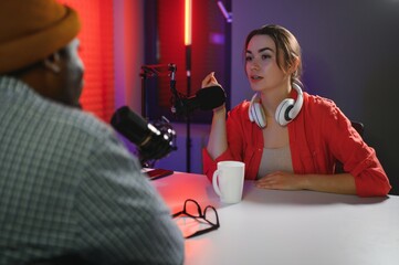 two radio hosts in headphones laughing while recording podcast in studio together