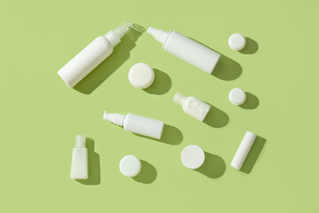 Composition with different travel cosmetic bottles and jars on green background