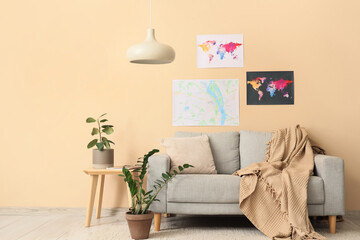 Sofa, houseplants and world maps on beige wall in living room