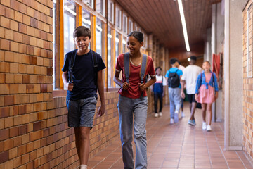 Walking in school hallway, students with backpacks talking and smiling