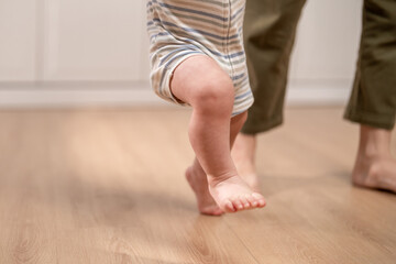 Close up of a baby's tiny feet stepping on the floor learns to walk. 