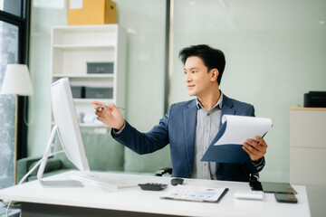  Asian businessman working with working notepad, tablet and laptop documents talking on the...