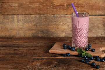 Glass of fresh blueberry smoothie with mint and berries on wooden background