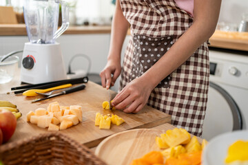Close up of woman making fresh fruit smoothies in blender in kitchen.