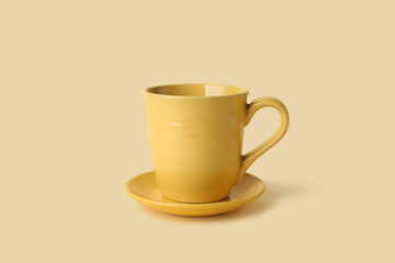 Yellow ceramic empty mug with saucer on beige background