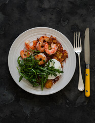 Potato latkes, shrimp, arugula - delicious breakfast, brunch, snack, tapas on a dark background, top view