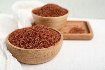 Tray with bowls of raw brown rice on white background