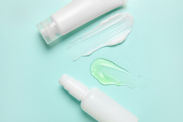 Bottles of cosmetic products and samples on color background