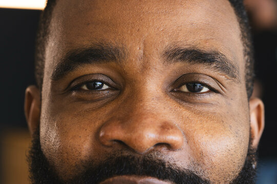 Close-up of man's face with thoughtful expression, focusing on eyes and beard, at home