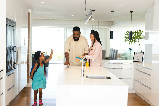 Happy family enjoying time in modern kitchen, Happy parents reading while child playing, at home