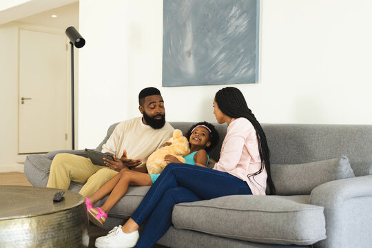 Holding teddy bear, child with Happy family smiling on sofa together, at home
