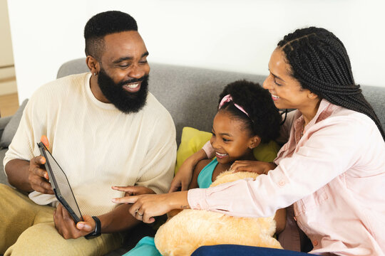 Happy family enjoying quality time together on couch, smiling and using tablet, at home