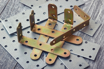 Collection of metal brackets and perforated metal plates for construction and woodworking for structural support. L-brackets and flat plates connection equipment.
