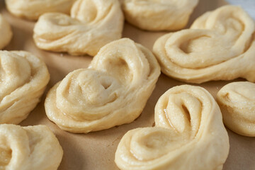 Raw buns on baking paper, close-up. Preparing for baking