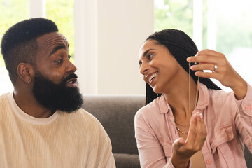 Happy couple at home joyfully sharing moment while holding necklace together
