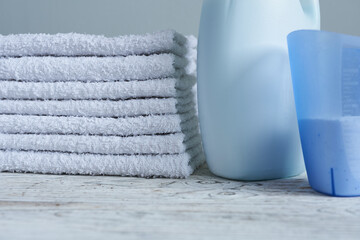 towels and laundry detergents on white wooden background, close-up