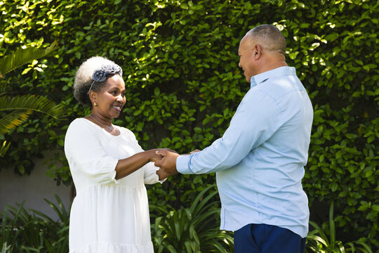 At wedding, Senior couple holding hands and smiling together in lush garden setting