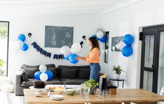 Woman decorating living room with balloons for birthday celebration at home