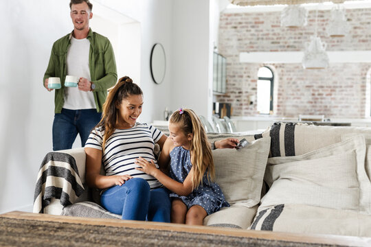 Family enjoying quality time at home, daughter sitting with parents on sofa, copy space