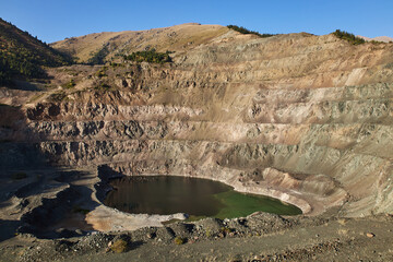 Open mining pit in mountain. Open-pit quarry, mine landscape, pond. Historical travel destination place Ak-Tyuz, Kyrgyzstan. Abandoned Kyrgyz mining and metallurgical plant. lead mining, deposit