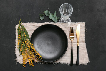 Beautiful table setting with mimosa flowers and eucalyptus on black background