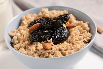 Bowl of tasty oatmeal with prunes and almonds, closeup