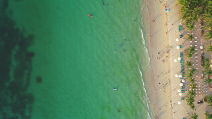 Aerial view of Cagban Beach in Boracay Island, Philippines, showing tourists enjoying the crystal clear turquoise water and white sand beach, lined with palm trees and beach umbrellas © Goinyk