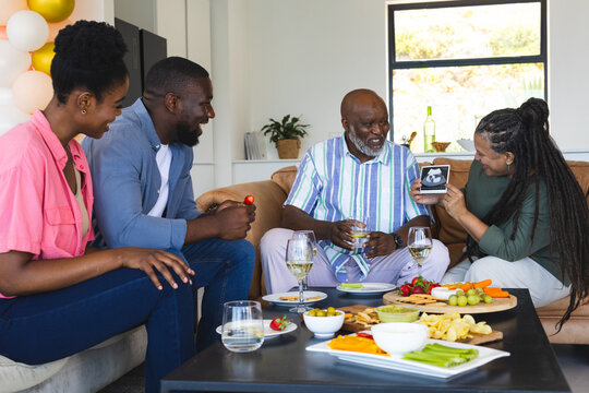 Family enjoying time together, sharing memories on smartphone at home celebration