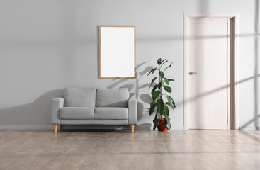 Interior of living room with grey sofa, plant and blank frame