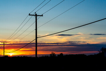 Power transmission line poles against the sky at sunset