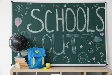 Shelf with backpack, books, globe and text SCHOOL'S OUT on blackboard in classroom
