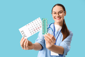 Female doctor with menstrual calendar and birth control pills on blue background